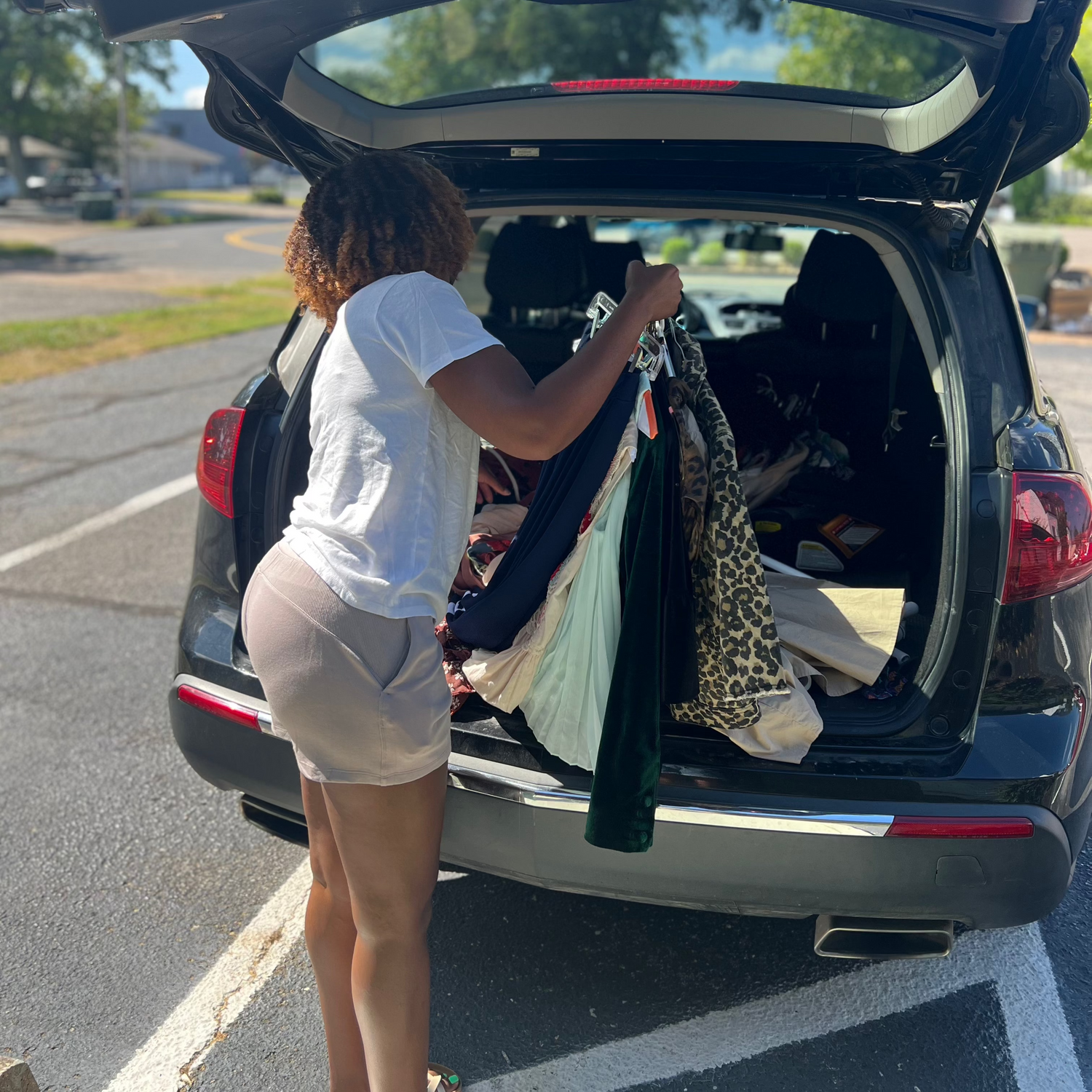 Person loading items into the trunk of a car in a parking lot.
